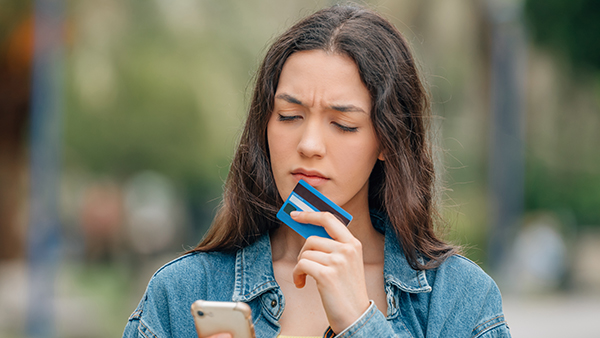 girl with mobile phone and credit card suspecting phishing and theft