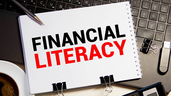 Financial Literacy is written on the book and placed on the laptop